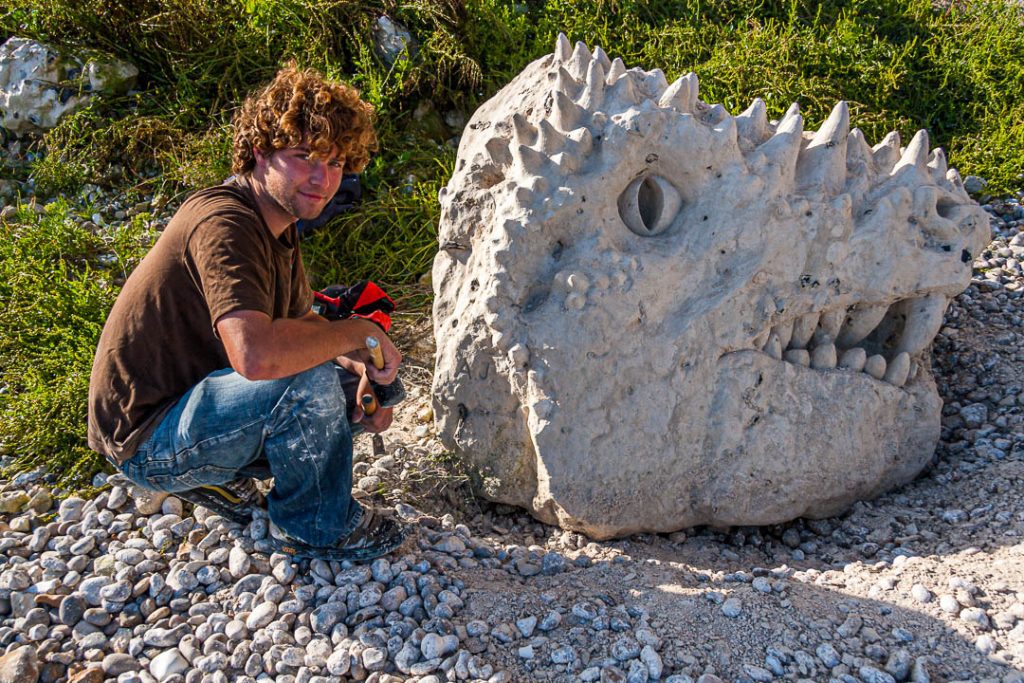 An artist creates a dinosaur head he hews out of a chalk rock on the Jurassic Coast in Beer, England / © Foto: Georg Berg