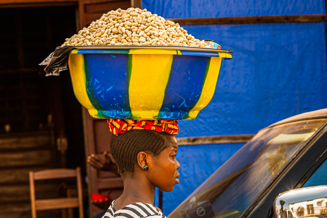 Afrikanische Verkäuferin trägt eine Schüssel mit Erdnüssen auf dem Kopf / © Foto: Georg Berg