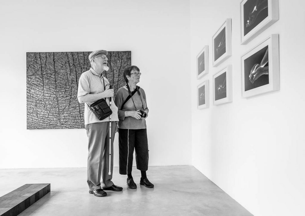 Ehefrau erklärt ihrem blinden Ehemann die Bilder einer Ausstellung