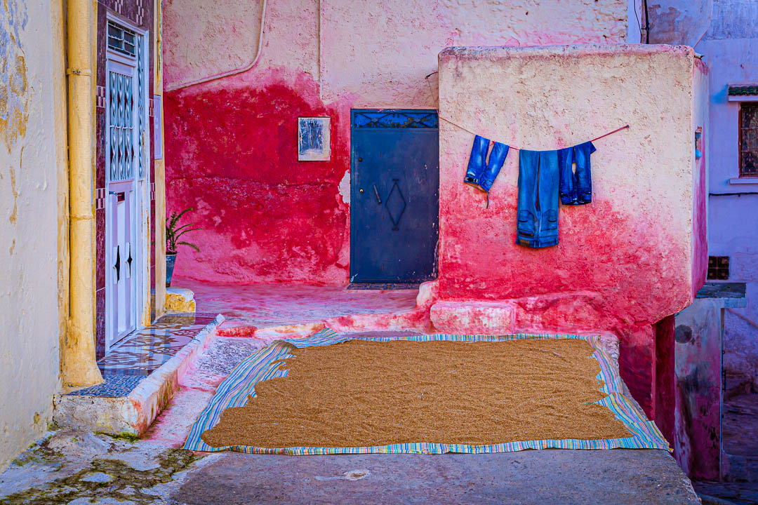 Blau und Rot. Jeans und Getreide trocknen vor einem Wohnhaus an der Luft / © Foto: Georg Berg