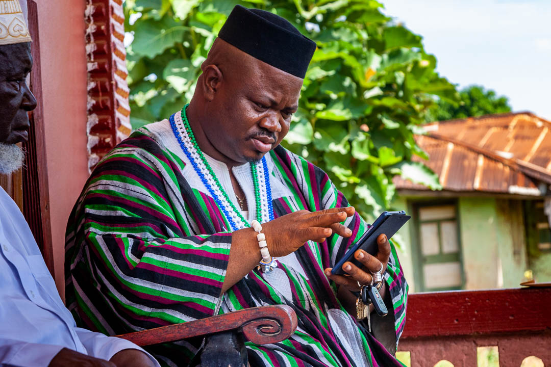 Paramount chief P.C. Grawuru III. on his throne texting with his smart phone / © Foto: Georg Berg